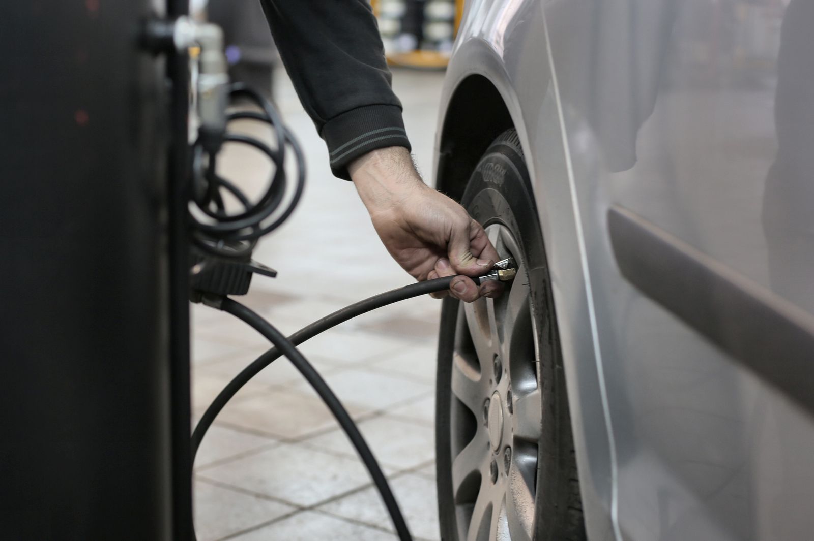 Main qui gonfle un pneu au flexible d’air comprimé